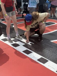 A race fan signs the painted start-finish line area at Darlington Raceway during the 2026 Cook Out Southern 500 weekend.