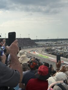NASCAR Cup Series cars race through a turn at Darlington Raceway during the 2026 Cook Out Southern 500 as fans watch from the grandstands.