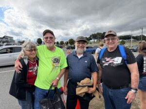 Four RaceAway guests gather outside Charlotte Motor Speedway before the October 2026 Bank of America 400, with two wearing No. 9 NASCAR gear.