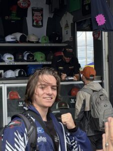 A RaceAway guest poses near a NASCAR merchandise hauler while an autograph signing takes place during the October 2026 Bank of America 400 weekend at Charlotte Motor Speedway.