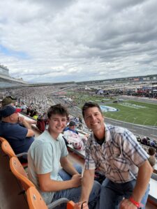 Two RaceAway guests smile from their seats with a panoramic view of Charlotte Motor Speedway before the October 2026 Bank of America 400.