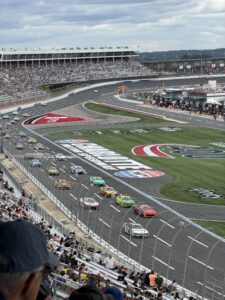 NASCAR Cup Series cars race through Charlotte Motor Speedway during the October 2026 Bank of America 400, with the grandstands and infield in view.