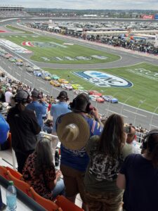 The NASCAR Cup Series field competes at Charlotte Motor Speedway during the October 2026 Bank of America 400, with fans watching from the grandstands and the speedway infield stretching across the scene.
