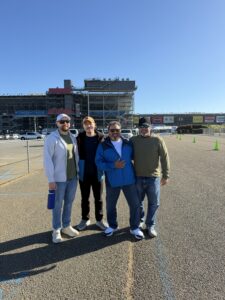 Four RaceAway guests pose outside Talladega Superspeedway during the October 2026 YellaWood 500 weekend.